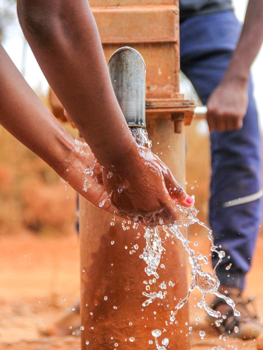 Hands being washed at a rural water pump