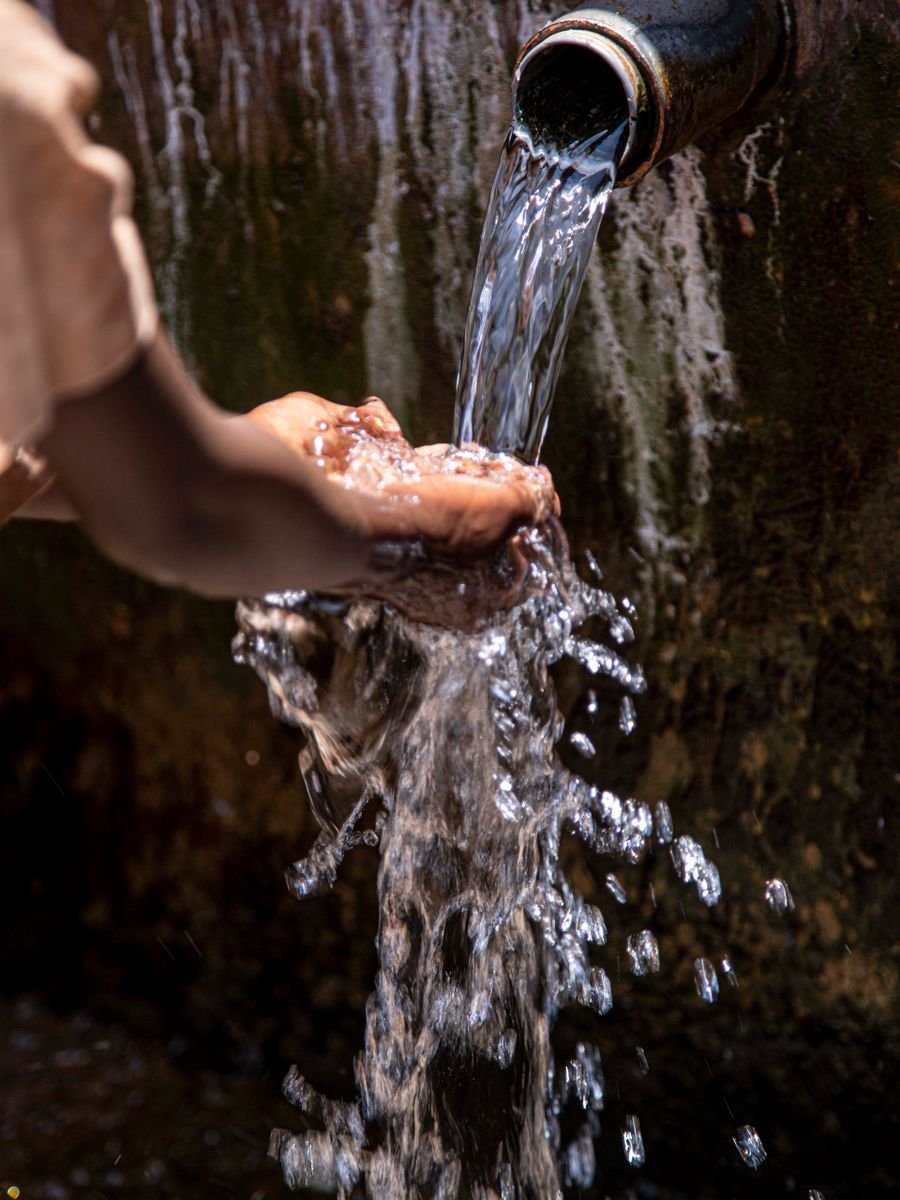 Hands catching clean water from a pipe